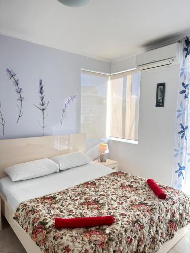 a bedroom with a large bed with a red pillow on it at Violet Sea View Apartment in Sarandë