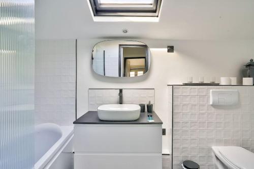 a white bathroom with a sink and a mirror at Splendide T2 à proximité du Parc Georges Brassens in Paris