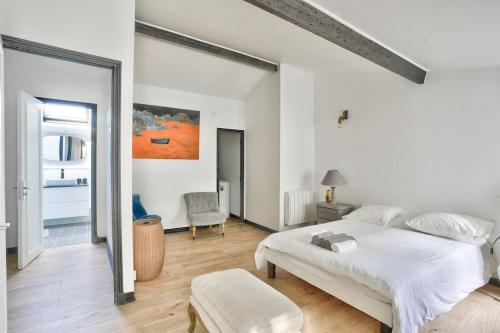 a white bedroom with a large bed and a chair at Splendide T2 à proximité du Parc Georges Brassens in Paris