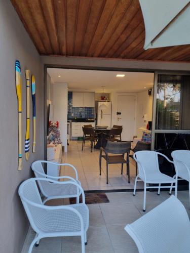 a patio with white chairs and a living room at Porto Central Residence 01 in Porto De Galinhas