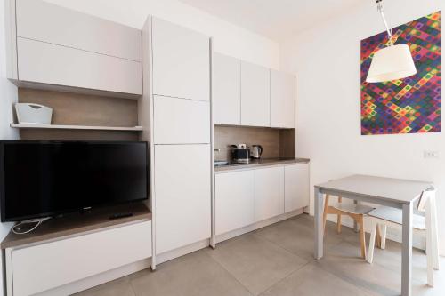 kuchnia z białymi szafkami, stołem i telewizorem w obiekcie Rivin Apartment w Mediolanie