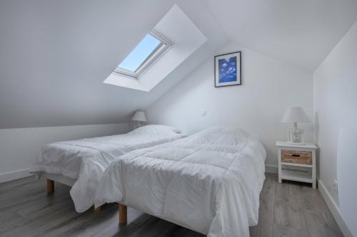- 2 lits dans une chambre blanche avec fenêtre dans l'établissement Appartement pour 4 - 300m de la plage de la Baule, à La Baule