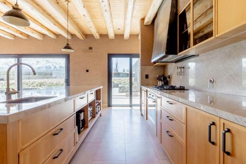 a large kitchen with wooden cabinets and a large window at Rancho Adobe Eco Hotel in Tupungato