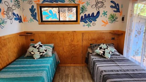 2 camas en una habitación con papel pintado colorido en HARE O HAUPIANO, en Hanga Roa