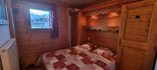 1 dormitorio con 1 cama en una cabaña de madera en travelski home premium - Résidence Les Hauts Bois 4 stars, en Aime La Plagne