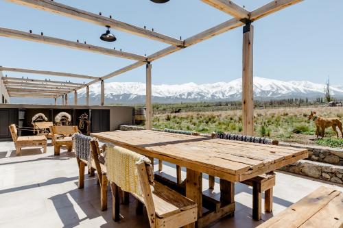 an outdoor patio with a wooden table and chairs at Rancho Adobe Eco Hotel in Tupungato
