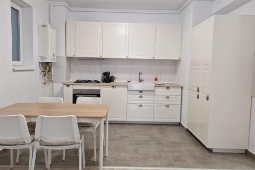 a kitchen with white cabinets and a table and chairs at Lovely apartment in City Center in Timişoara
