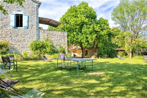 une table dans l'herbe devant un bâtiment dans l'établissement Gîte 2/3p, 80m2, Terrasse ombragée, parc, à Villeuneuve-de-Berg