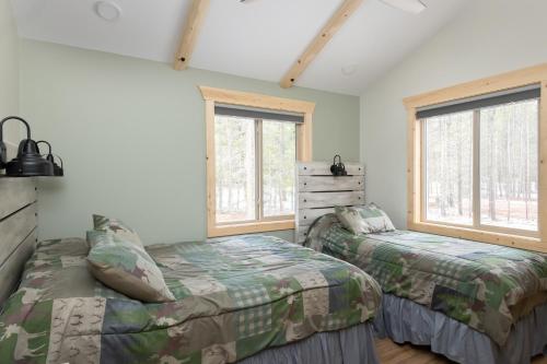 2 Betten in einem Schlafzimmer mit 2 Fenstern in der Unterkunft The Golden Eagle Cabin in Valemount