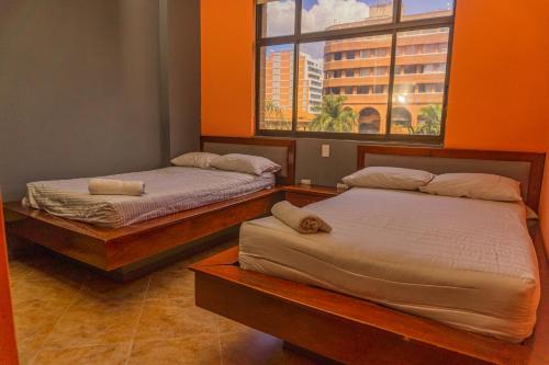 2 camas en una habitación con ventana en hotel journey, en Medellín