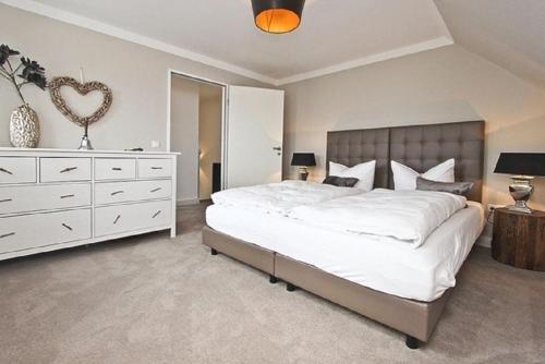 ein Schlafzimmer mit einem großen weißen Bett und einer Kommode in der Unterkunft Apartment Ostseerausch in Scharbeutz