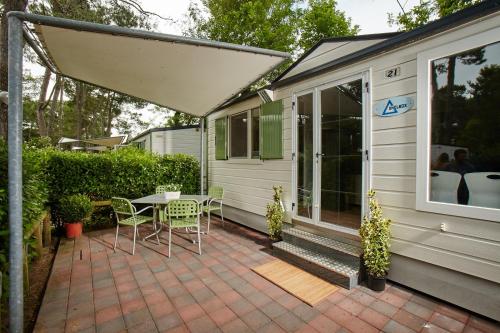 a patio with a table and chairs next to a house at Dei Fiori Camping Village in Cavallino-Treporti