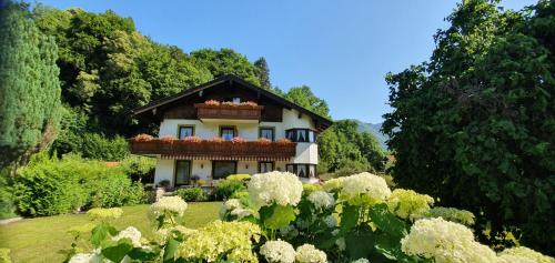 a house with a balcony in a garden with flowers at Landhaus Weiß in Bad Reichenhall