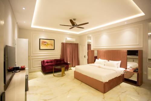 a bedroom with a bed and a couch and a ceiling fan at The Edition Bahawalpur in Bahawalpur
