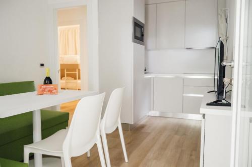 a white kitchen with white chairs and a table at Dei Fiori Camping Village in Cavallino-Treporti