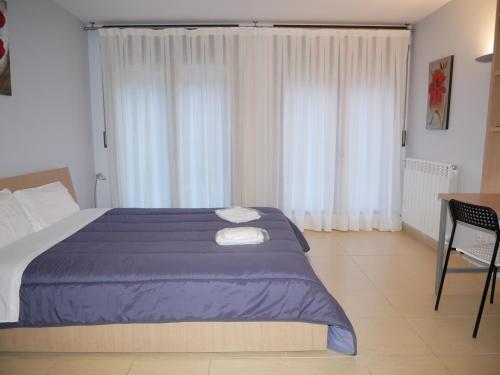 een slaapkamer met een groot bed, een bureau en een raam bij Saüc-Vacances Pirinenca in Canillo