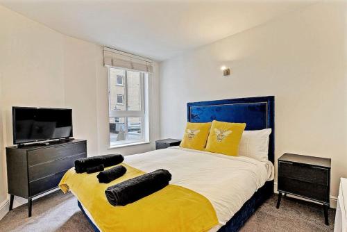 1 dormitorio con 1 cama grande con almohadas amarillas y TV en Radiant 2BR Tower Bridge Oasis with Rooftop Deck en Londres