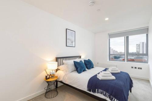 a bedroom with a bed with blue pillows and a window at Central 2BR Urban Haven Rooftop Terrace in Bracknell