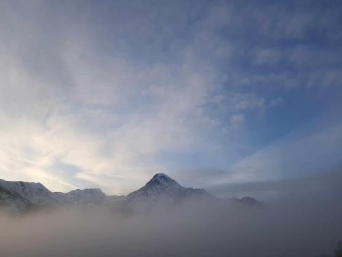 a mountain obscured by a layer of fog in the sky at Cottage Paradise in Kazbegi