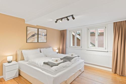 a large white bed in a room with windows at TOP Apartments - Moderne Altbauwohnung im Zentrum Ludwigsburg - Kingsize Bett - Netflix - 80qm - 24h Check-In in Ludwigsburg