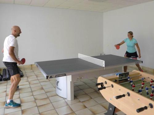 two people standing in a room with a ping pong table at Hotel Le Chalet in Sainte-Marie-de-Campan