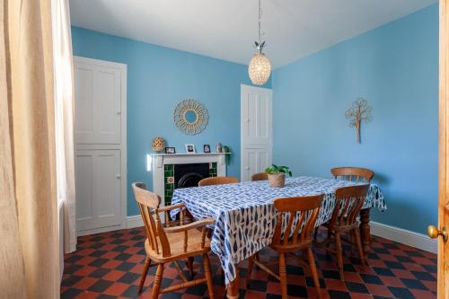 a blue dining room with a table and chairs at Family Home with Bunk Beds, Courtyard, TV & Beach in Pembrokeshire