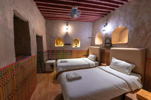 a room with two beds and two windows at Antique Inn in Nizwa