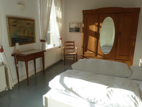 a bedroom with a bed and a table and a mirror at Hof Homfeld in Ditzum