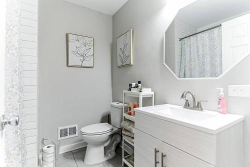 a white bathroom with a toilet and a sink at Cozy Cumberland ATL Home w Hot Tub in Atlanta