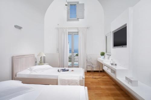 ein weißes Schlafzimmer mit einem Bett und einem Fernseher in der Unterkunft Akrotiri Private Residence in Fira