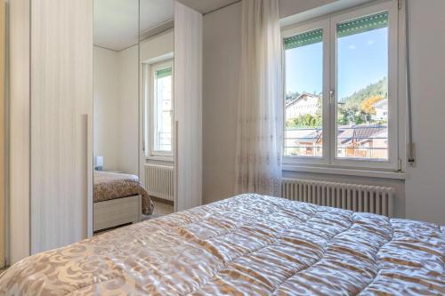 ein Schlafzimmer mit einem Bett und einem großen Fenster in der Unterkunft Casa Maggiorina, Levico Terme Ospitar in Levico Terme