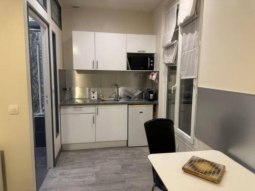 a small kitchen with white cabinets and a table at Chic studio near chatelet les halles in Paris