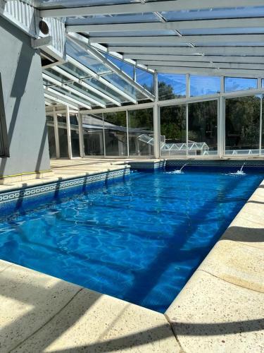 een groot zwembad met blauw water in een gebouw bij Casa con pileta climatizada privada in Bariloche