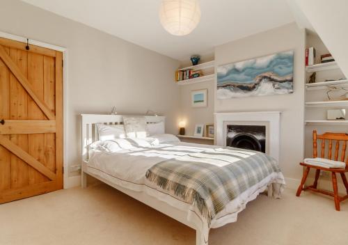 a white bedroom with a bed and a fireplace at The Lobster Pot in Orford