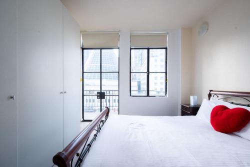 メルボルンにあるNOVA - Inner City Double Storey Loft With Viewsのベッドに赤いハートの枕が置かれた白い寝室