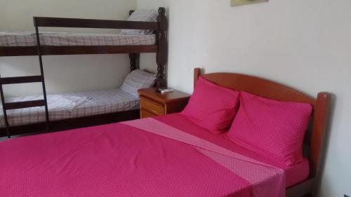 um quarto com uma cama rosa e 2 beliches em Pousada Costa da Praia na Praia Grande