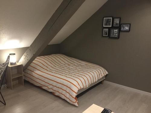 - une chambre avec un lit, une table et des photos sur le mur dans l'établissement Studio, étage 3, spacieux refait à neuf, à Belfort