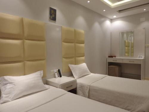 Habitación de hotel con 2 camas y espejo en نيو العرين بارك أبها, en Abha