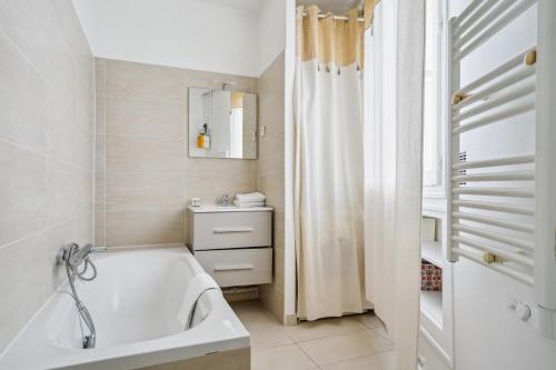 une salle de bain blanche avec une baignoire et un lavabo dans l'établissement Luxury Apartment La Tour Paris, à Paris
