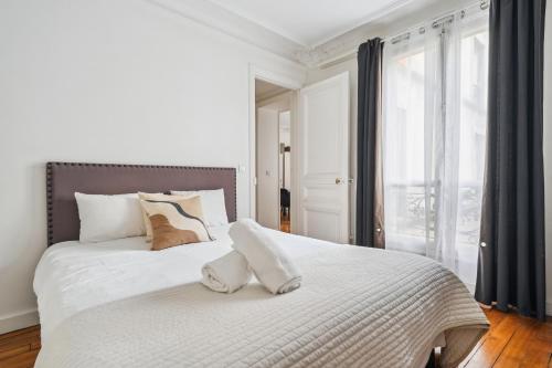 un lit blanc avec deux oreillers dessus dans l'établissement Luxury Apartment La Tour Paris, à Paris