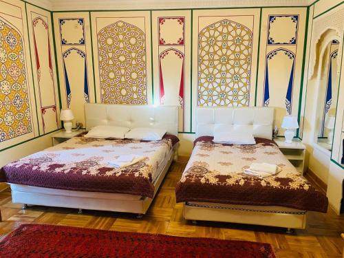 two beds sitting next to each other in a bedroom at "CHOR MINOR" BOUTIQUE HOTEL Bukhara Old Town UNESCO HERITAGE List Est-Since 2003 Official Partner of Milano La Rosse Aroma in Bukhara