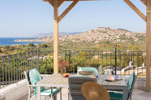 einen Tisch und Stühle auf einem Balkon mit Meerblick in der Unterkunft Lampetos Houses Molyvos in Mythimna