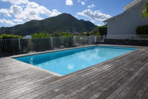 a swimming pool with a wooden deck and a mountain at Villa Ukarimu in Cul de Sac