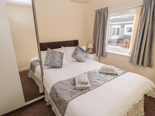 a bedroom with a large white bed with a mirror at Primrose Cottage in Chathill