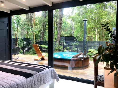 a bedroom with a large window and a tub on a deck at Calma Cabins in Puerto Clocker