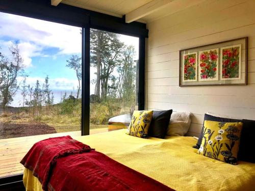 a bedroom with a bed and a large window at Calma Cabins in Puerto Clocker