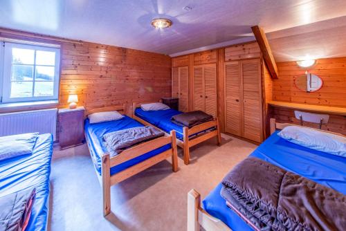 a room with three beds in a wooden cabin at A Tchapè Mèlé in Gouvy