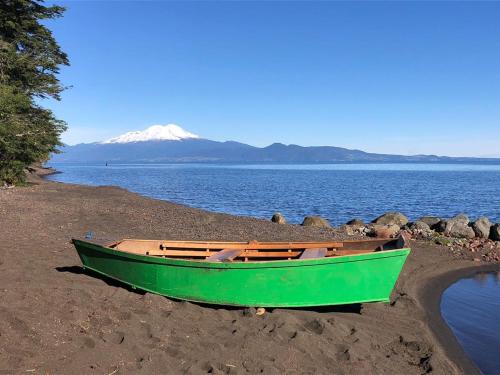a green boat sitting on the shore of a beach at Calma Cabins in Puerto Clocker