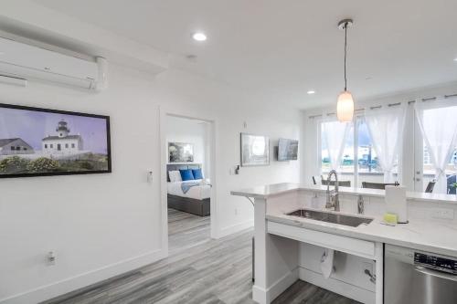 a white kitchen with a sink and a living room at Park Blvd Paradise 301 ADA compliant with a Spa in San Diego