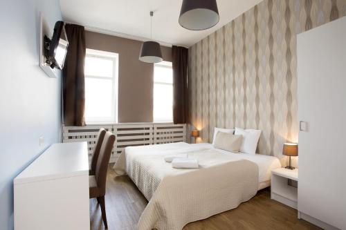 a bedroom with a white bed and a desk at Hotel Traffic Poznań Stare Miasto in Poznań